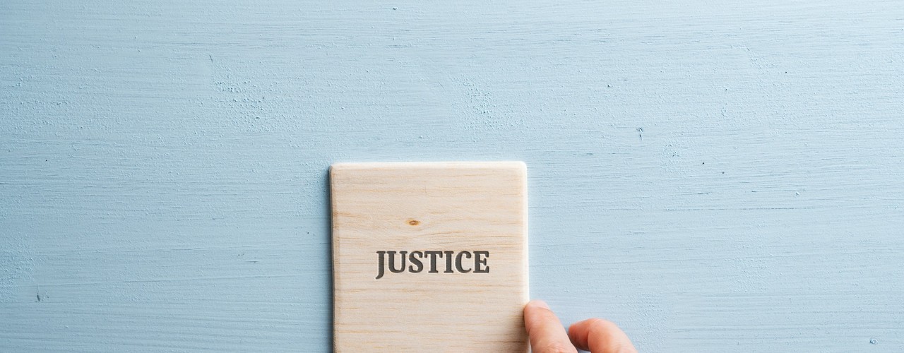 Le mot justice écrit sur du bois avec une main