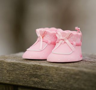 selective focus photography of pink shoes on wooden bench