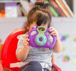 girl holding purple and green camera toy
