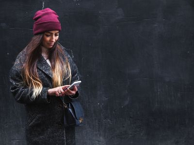 Happy beautiful woman enjoys on mobile phone on a black background