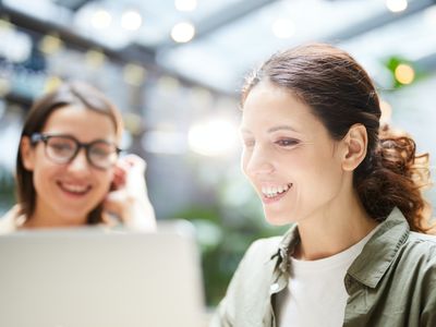 Deux femmes souriantes devant un ordinateur en train de programmer pour développer un site