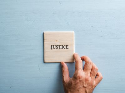 Le mot justice écrit sur du bois avec une main