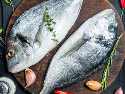 Raw sea fish dorado with spices and vegetables.