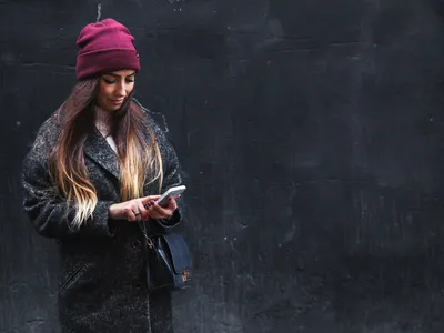 Happy beautiful woman enjoys on mobile phone on a black background