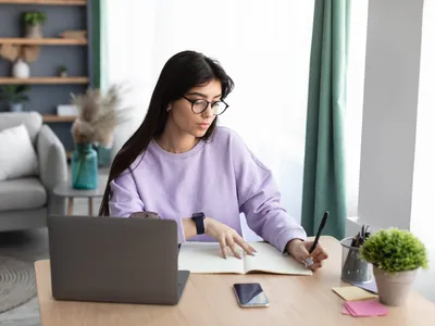 une femme en train de rédiger un article devant un ordinateur
