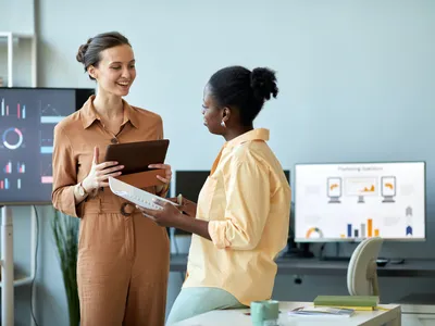 Young successful coach with tablet looking at African American female employee