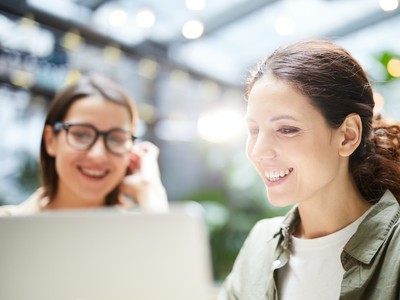 Deux femmes souriantes devant un ordinateur en train de programmer pour développer un site