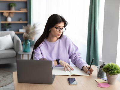 une femme en train de rédiger un article devant un ordinateur