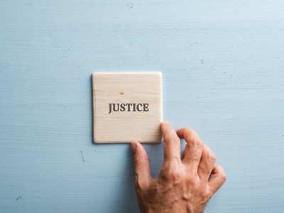 Le mot justice écrit sur du bois avec une main