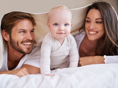 Photo recadrée d'un jeune couple allongé sur le lit avec leur petit garçon.