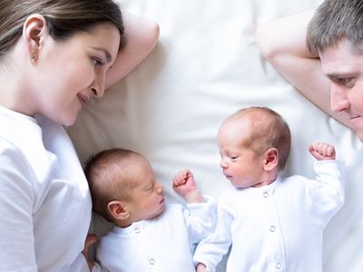 Newborn Identical twins on the bed, on a parents hands. Life style, emotions of kids. Infant Babies