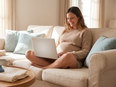 Femme enceinte créant sa cagnotte de naissance sur son ordinateur portable dans son salon