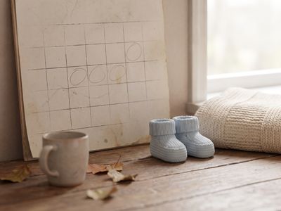Calendrier avec chaussons de bébé et plaid, symbole du délai pour participer à une cagnotte de naissance