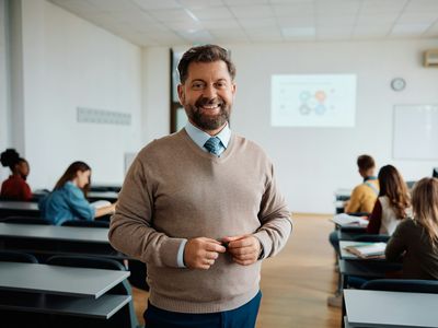 Happy university teacher in the classroom looking at camera.
