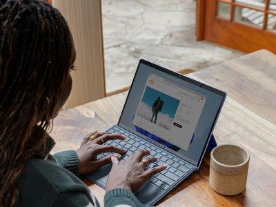 a woman sitting at a table using a laptop computer