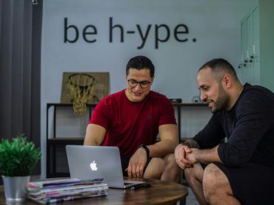 Deux hommes assis sur une table basse regardant un ordinateur portable