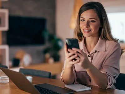 Jeune femme, ÃÂ©crivant un email d'invitation sur son tÃÂ©lÃÂ©phone.