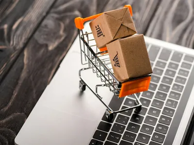 toy boxes in small shopping cart on laptop, e-commerce concept