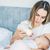 Mother feeding a newborn baby from bottle at home.