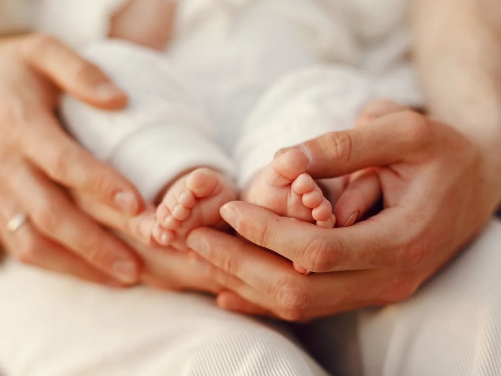 Pieds de nouveau-né dans les mains de ses parents