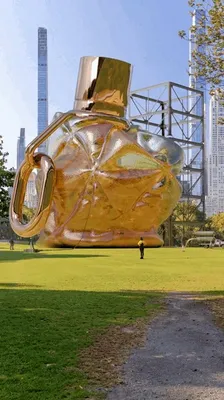 Flacon de parfum doré géant en CGI installé dans un parc urbain