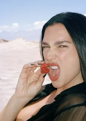 Portrait sensoriel d’une femme portant des framboises à la bouche, lumière de désert