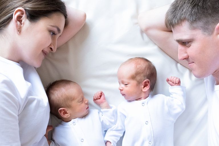 Newborn Identical twins on the bed, on a parents hands. Life style, emotions of kids. Infant Babies