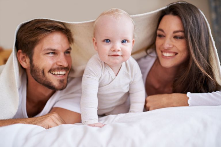 Photo recadrée d'un jeune couple allongé sur le lit avec leur petit garçon.